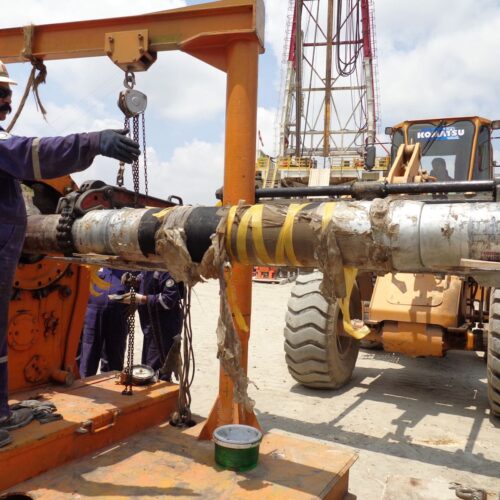 Workers performing maintenance on drill pipe.
