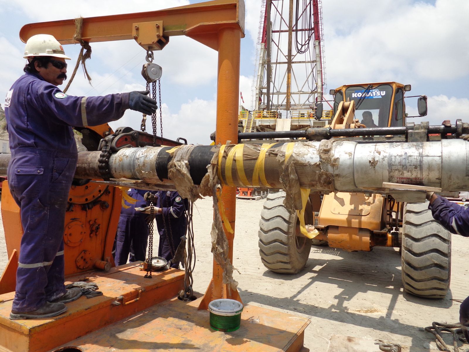 Workers performing maintenance on drill pipe.